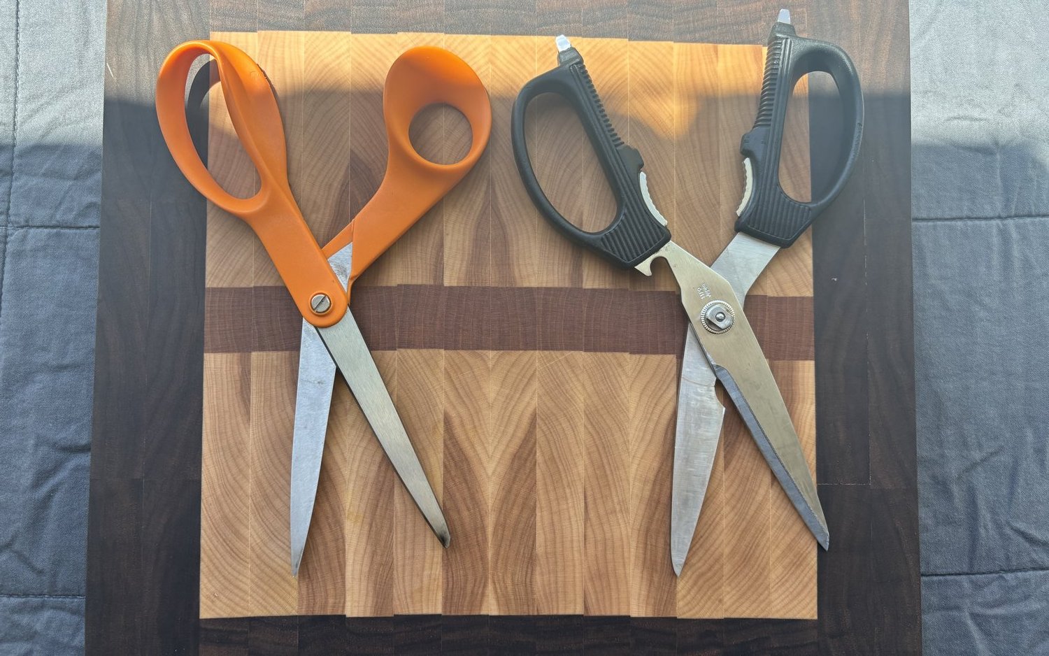 Kitchen shears and household scissors on a walnut cutting board
